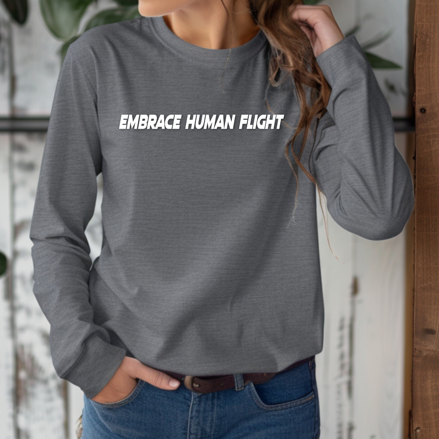 Person wearing a gray long-sleeve shirt with 'EMBRACE HUMAN FLIGHT' text.