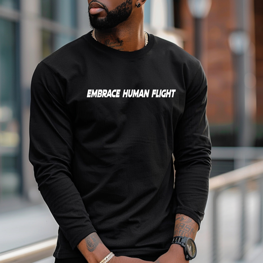 Person wearing a black long-sleeve shirt with 'EMBRACE HUMAN FLIGHT' text in an urban setting